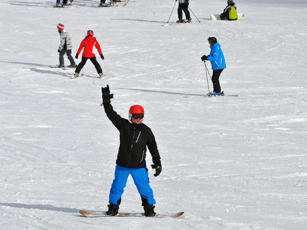 Skifahrer im Zielbereich hebt die Hand.